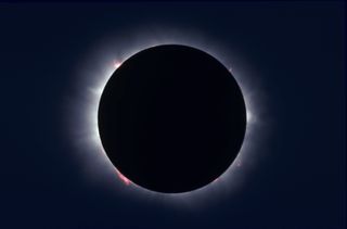a total solar eclipse. the moon appears as a black shadow while the sun is visible only as a white ring