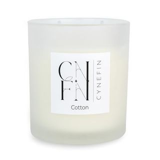 A white glass candle jar with a lit two wick candle inside. 