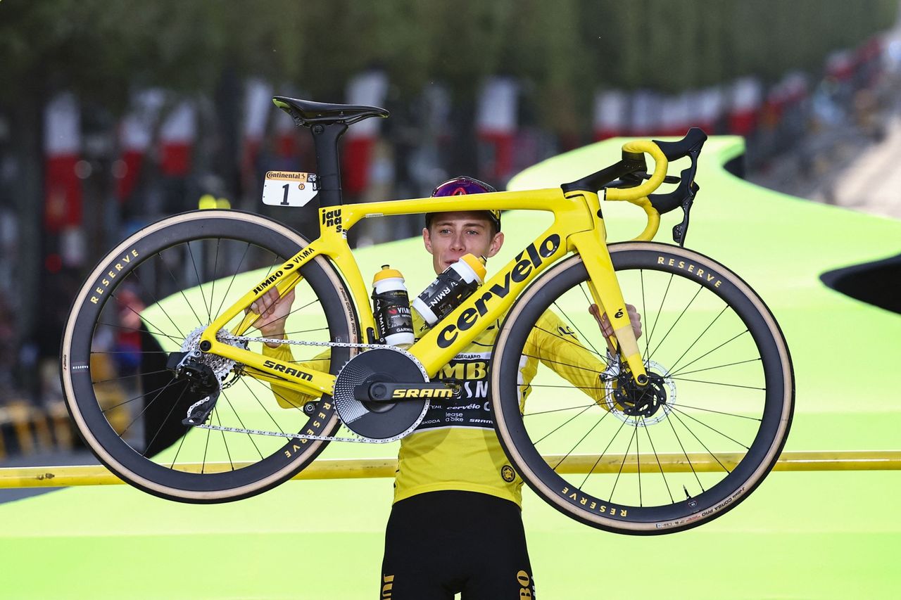 Jonas vingegaard on the podium at the tour de france 2023 holding his winning bike inthe air