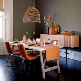 Grey dining room with wooden table and orange leather chairs and bird cage style hanging light