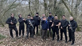 Tommy and Will Jessop stand in a wood with a stunt team holding guns in Tommy Jessop Goes to Hollywood.