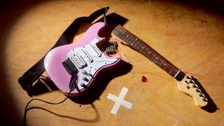 Pink guitar on the floor with the neck broken off