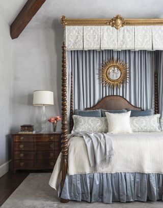 Bedroom with canopy bed, dark wood night stand, rug and gray walls