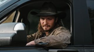 Luke Grimes looking out a truck window as Kayce in Yellowstone.