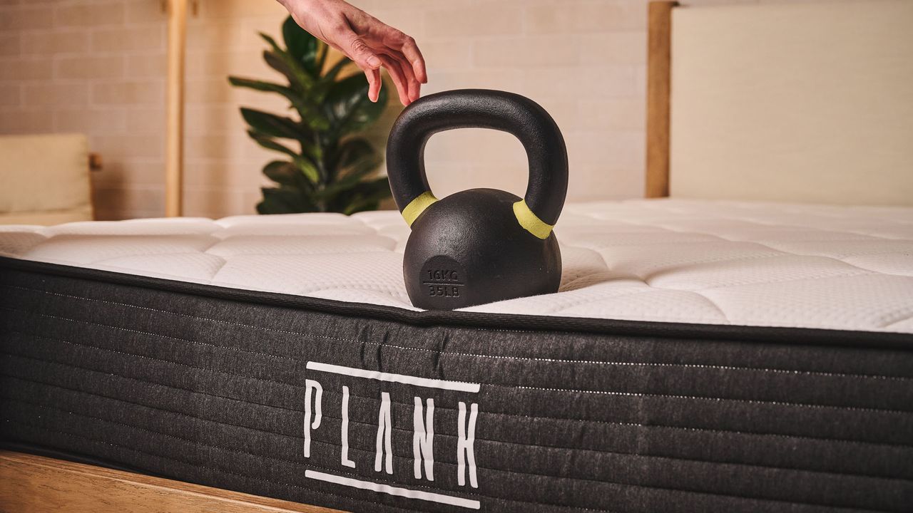 A closeup of a weight balancing on the end of the Plank Firm mattress. The weight hardly sinks into the surface, demonstrating the firm edge support of the memory foam
