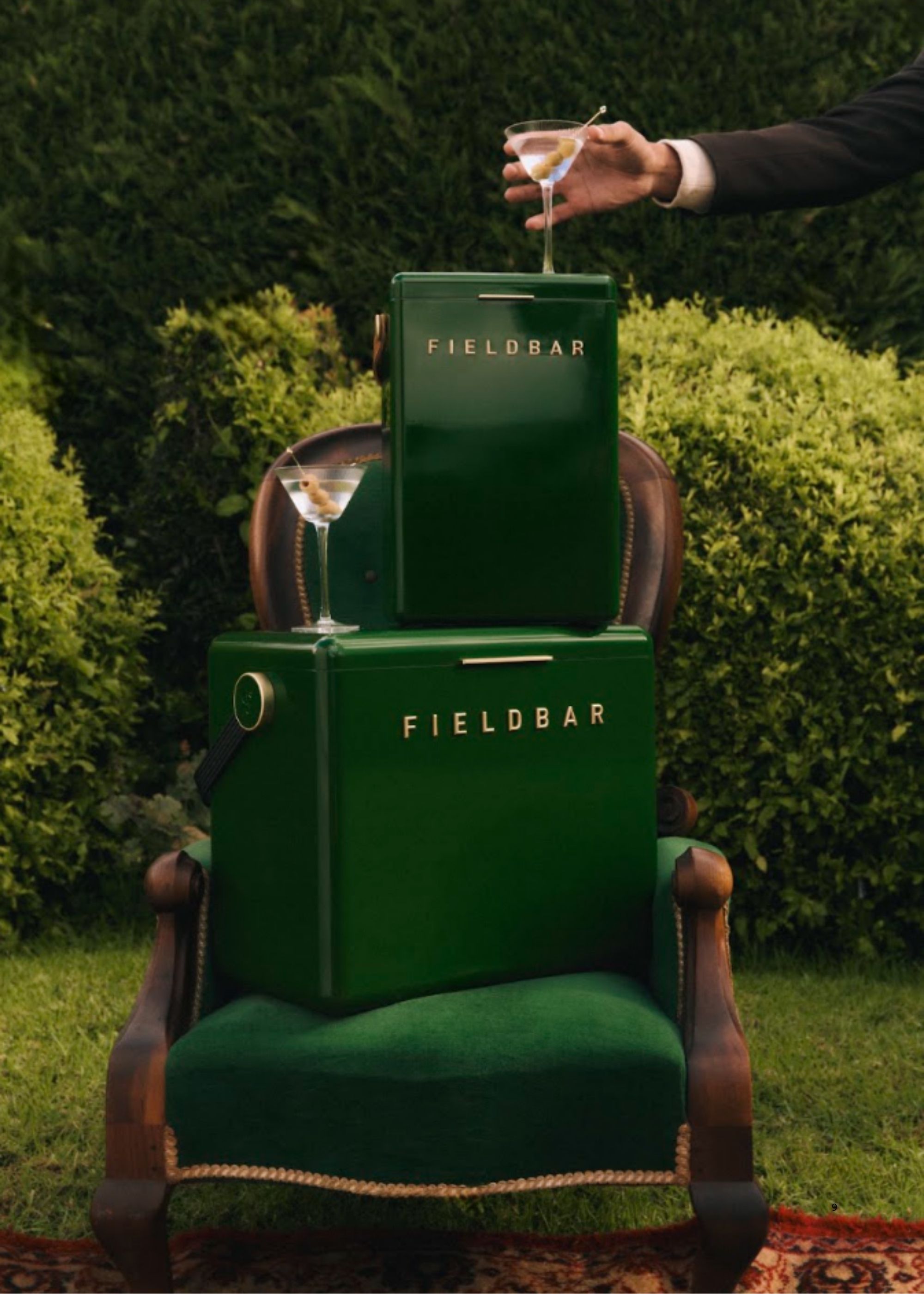 Image of two dark green fieldbar coolers stacked on a green chair in a garden with martini glasses on them.