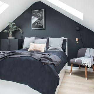 attic bedroom with black wall and wooden floor and chair