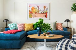 A living room with a blue corner sofa with lots of colorful throw pillows