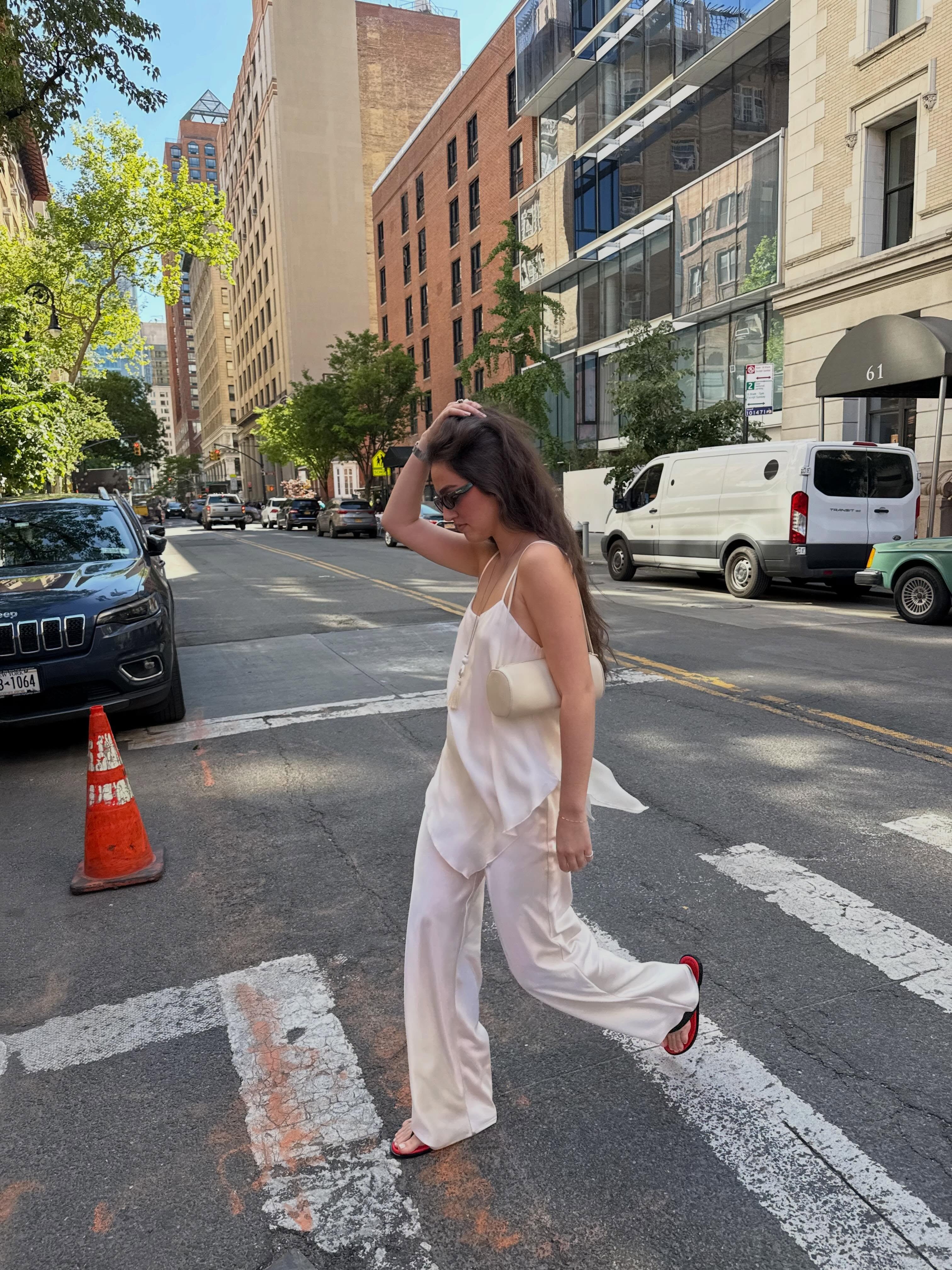 @briannaniebla wears the Reformation Jessie Sandal in red and black. She pairs them with satin trousers and a satin top.