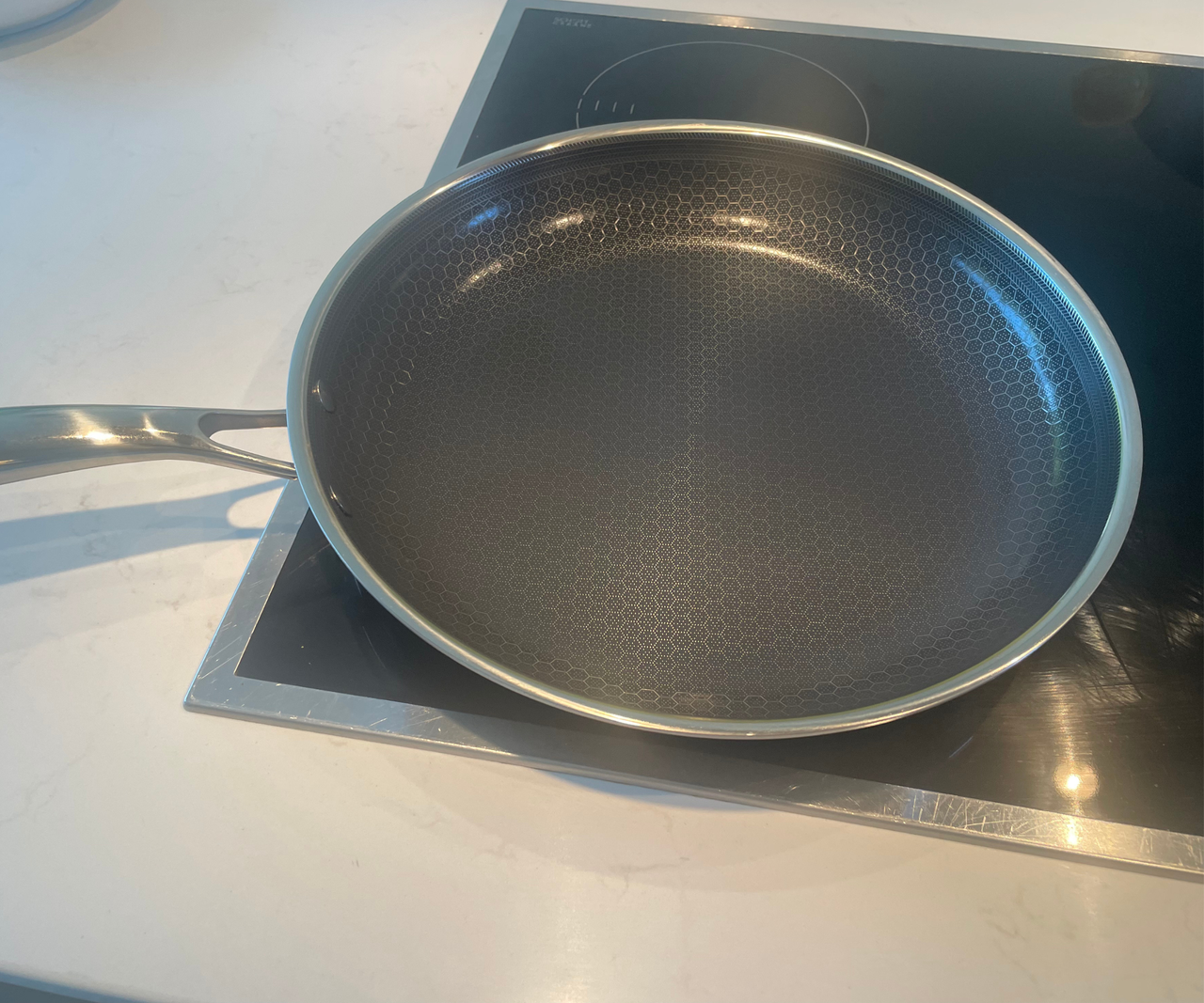 HexClad Hybrid Fry Pan on an electric hob, set into a white countertop.