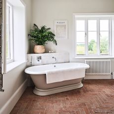 bathtub on stone flooring underneath plant in basket