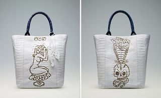 Left: white bag with black handle and a sketch of a nude woman in gold ink. Right: white bag with black handle and a design of a snake and a skull done in gold ink