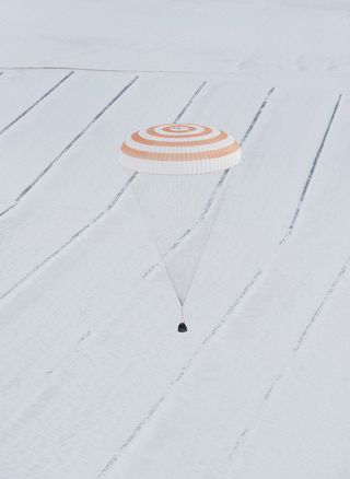 Soyuz spacecraft landing in Kazakhstan, the parallel lines in the snow hint at the presence of residents in the remote region. The spacecraft was returning to Earth after nearly six months in space at the International Space Station.
