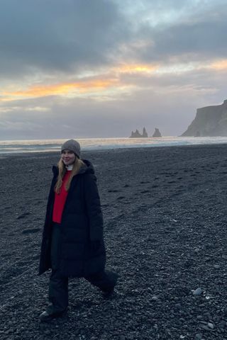 valeza wearing cold weather clothing from the article on a black sand beach
