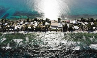 A horizontal aerial view of a thin occupied strip of land with buildings, with the ocean on each side