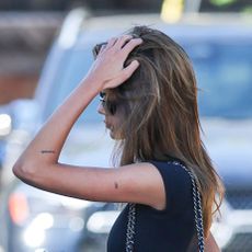 Kaia Gerber in L.A. wearing a black T-shirt, foldover bootcut leggings, a cobalt blue Chanel bag, and black leather ballet heels
