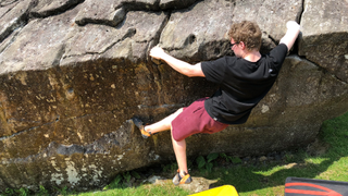 Matthew Phillips outdoors on a boulder