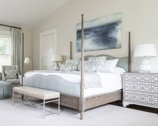A bedroom with pale blue bed linen and pale wood four poster bed illustrating simple bedroom ideas.