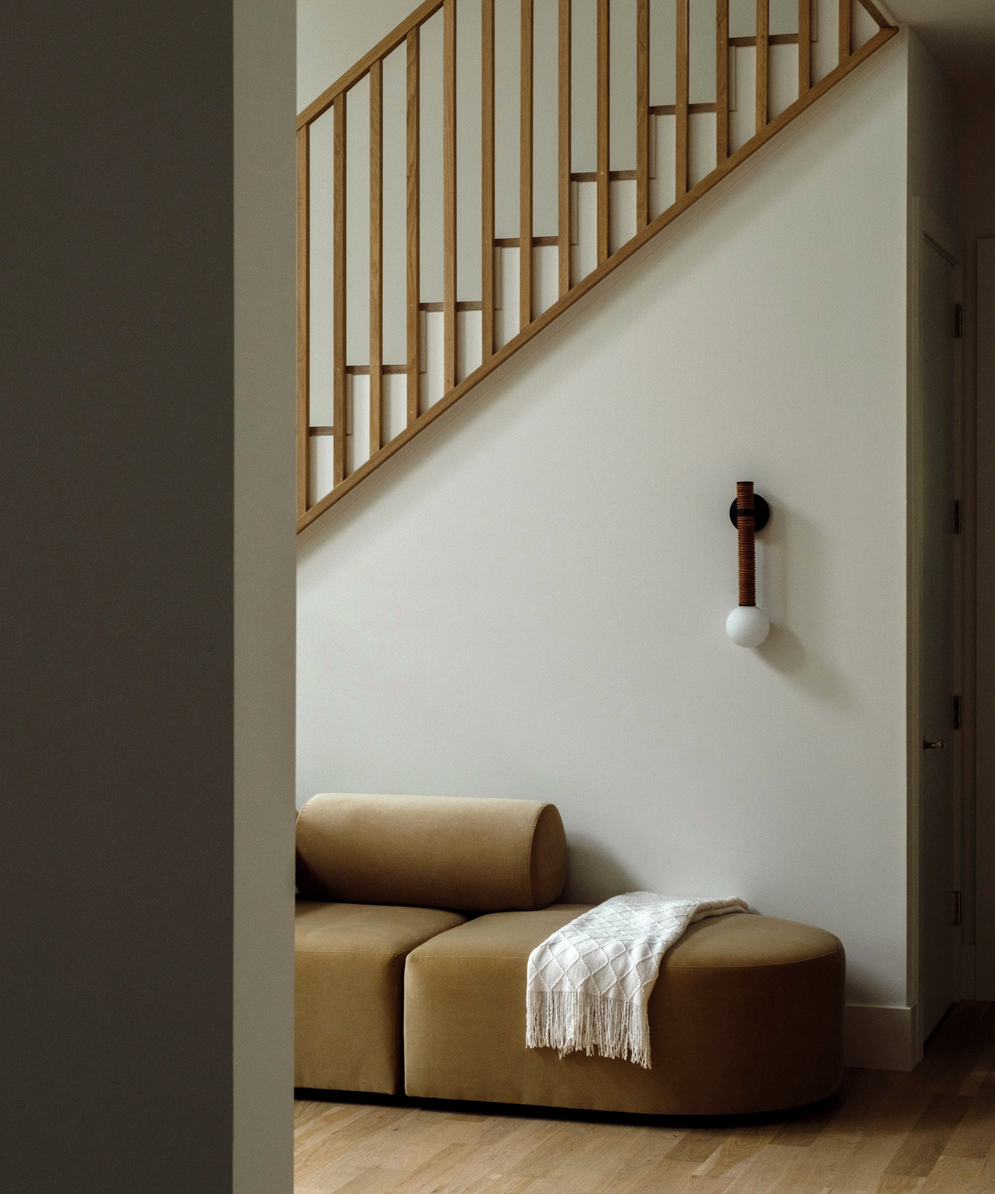 entryway with white walls, modern wall light and modern beige couch