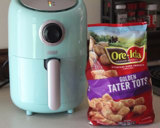 Dash 2-quart air fryer with bag of frozen tater tots