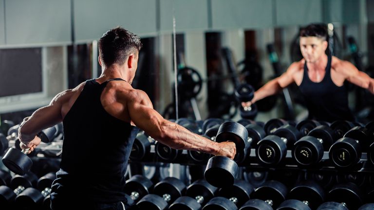 Athletic man working out in a gym with dumbbells