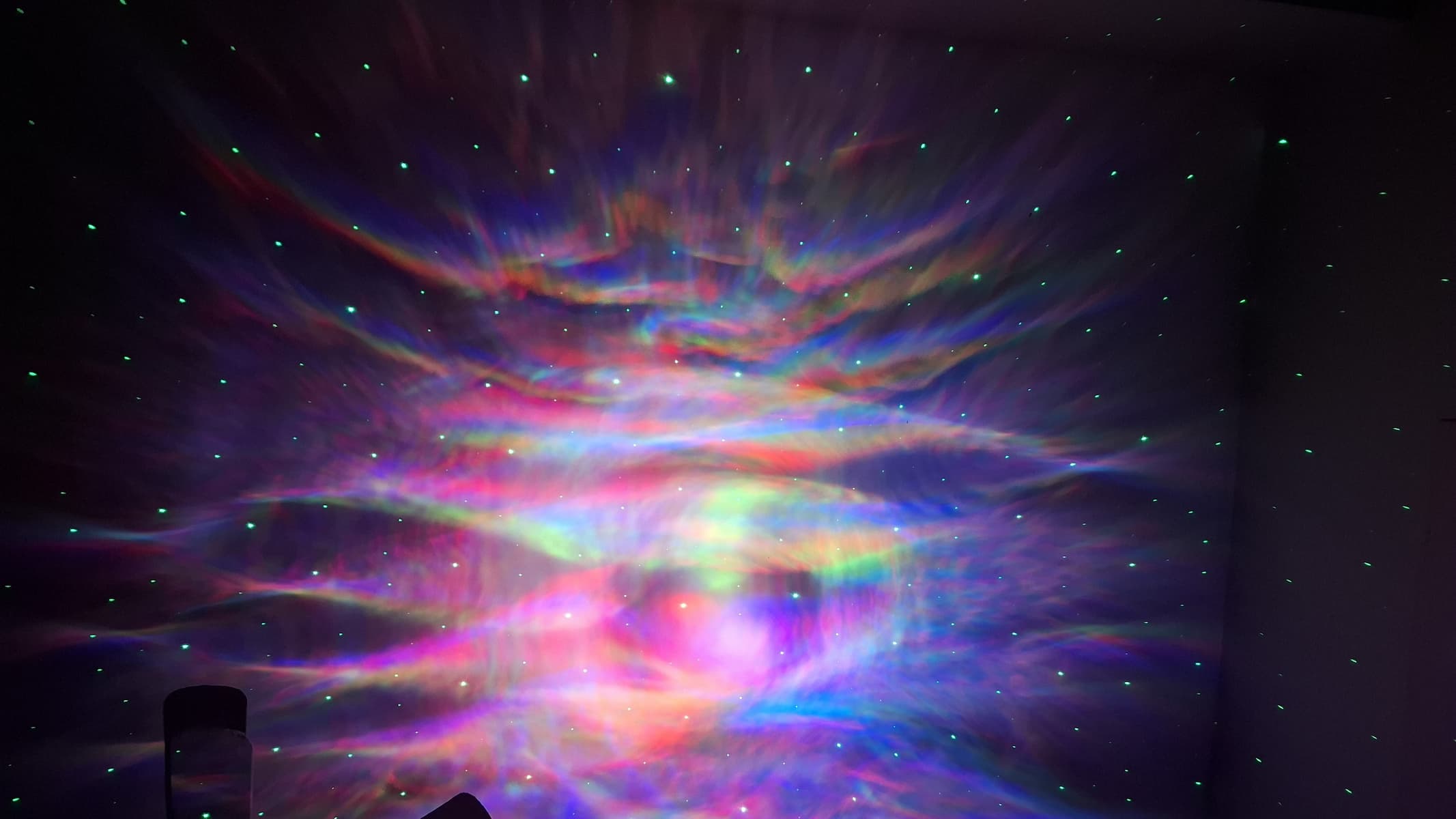 يوجد عرض متعدد الألوان به نقاط تمثل النجوم على الحائط في غرفة مظلمة.