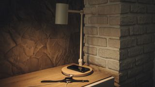 A smartphone placed on a lamp with a wireless charging pad built-in