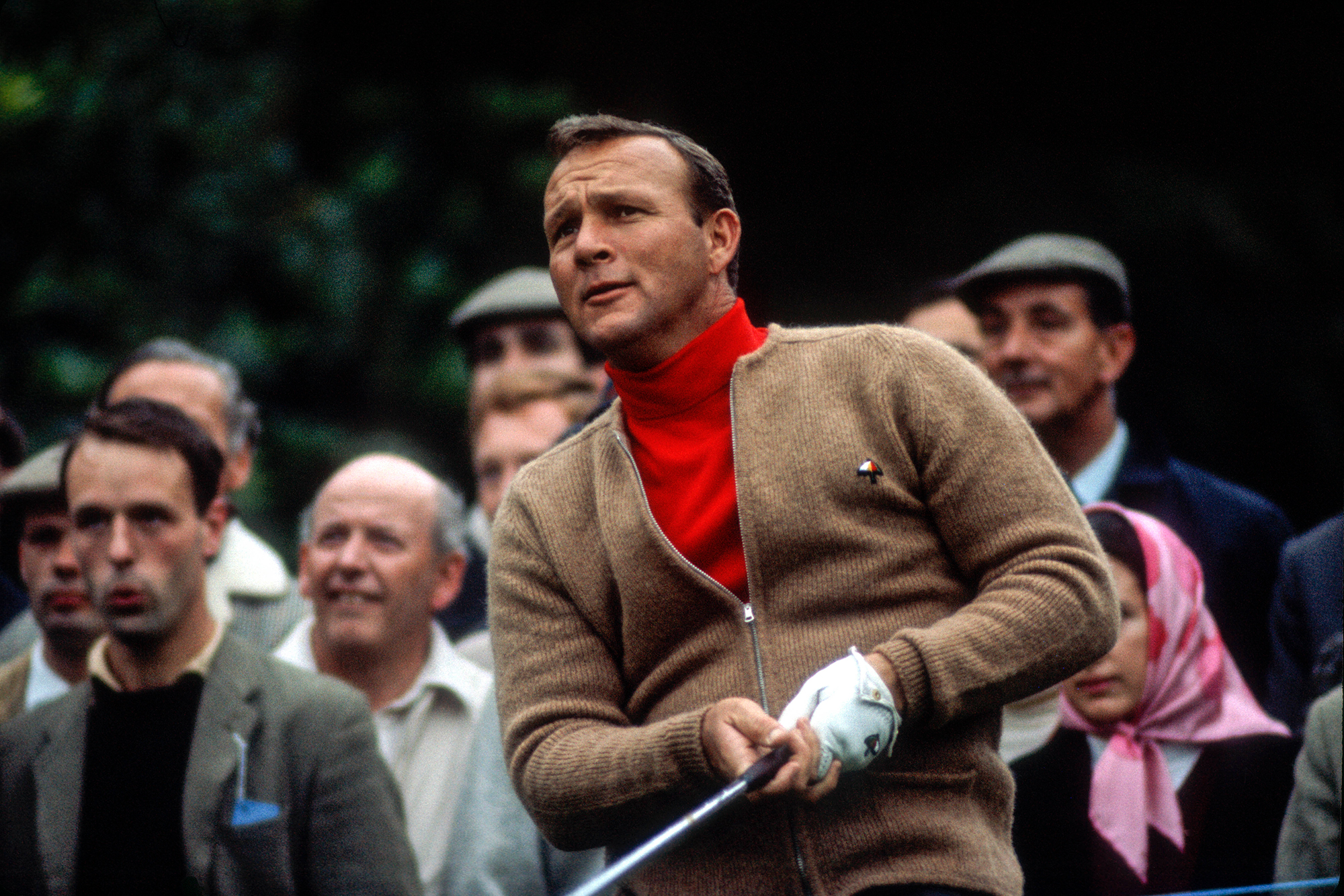 Arnold Palmer at the Piccadilly Match Play Championship wearing a red turtle neck shirt and a camel brown cardigan