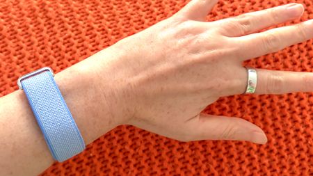 A close up of a hand wearing the Oura Ring 5 and a Fitbit Air
