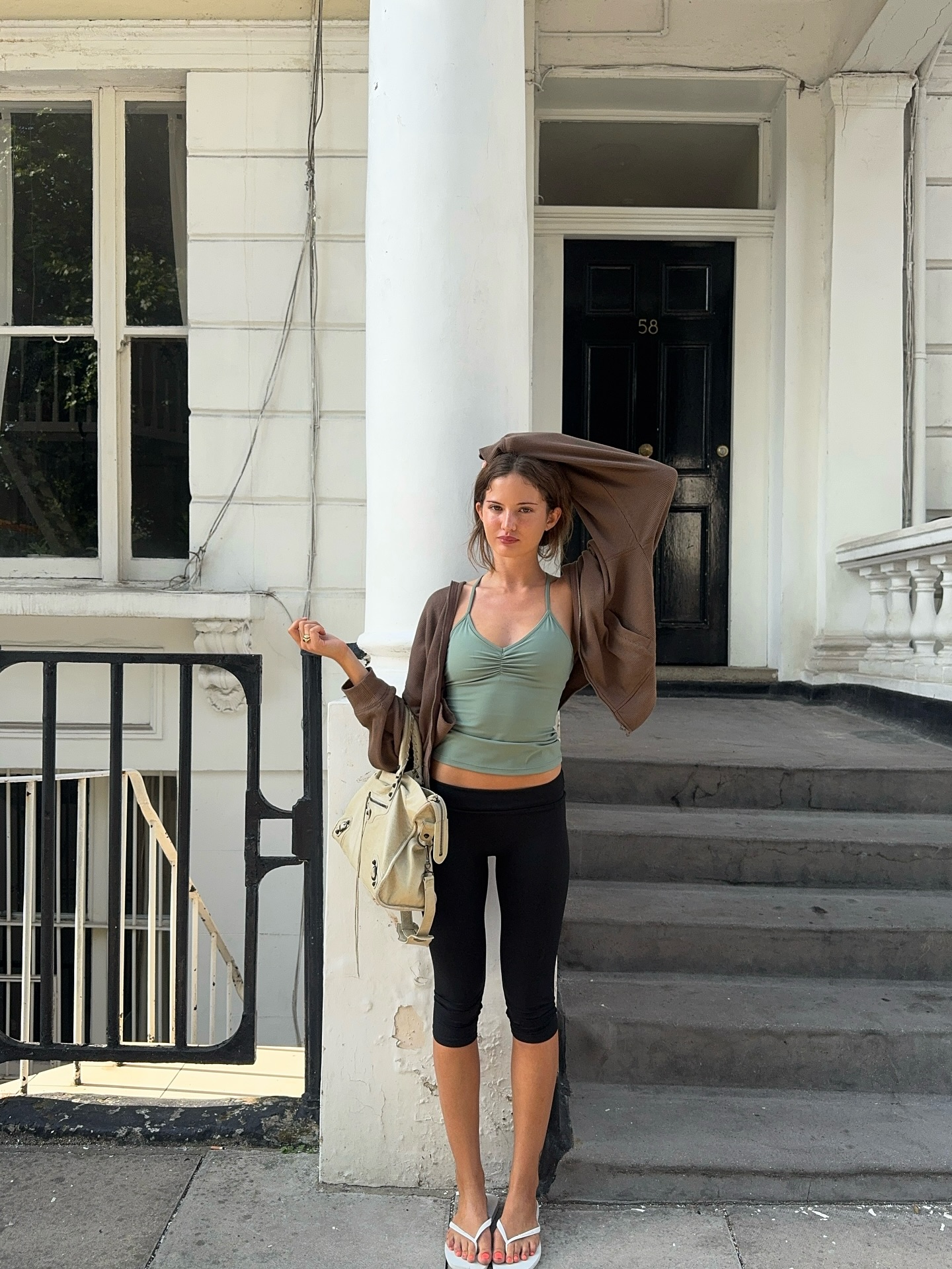 An image of @rubylyn_ wearing capri leggings, a spaghetti strap tank top, one of the biggest 2000s activewear trends coming back in 2026, with an oversized zip-up hoodie and square-toe flip-flops.