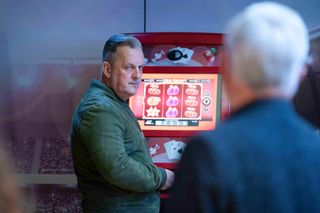 Harvey Monroe gives Rocky Cotton an unimpressed look next to a slot machine.