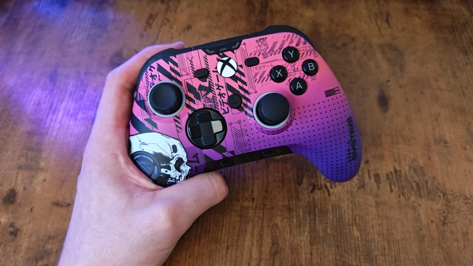 A reviewer holding a pink and blue version of the Scuf Valor Pro Wireless