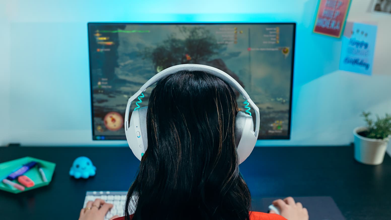 A woman, photographed from behind, sitting at a computer and wearing a Logitech G321 Wireless headset.