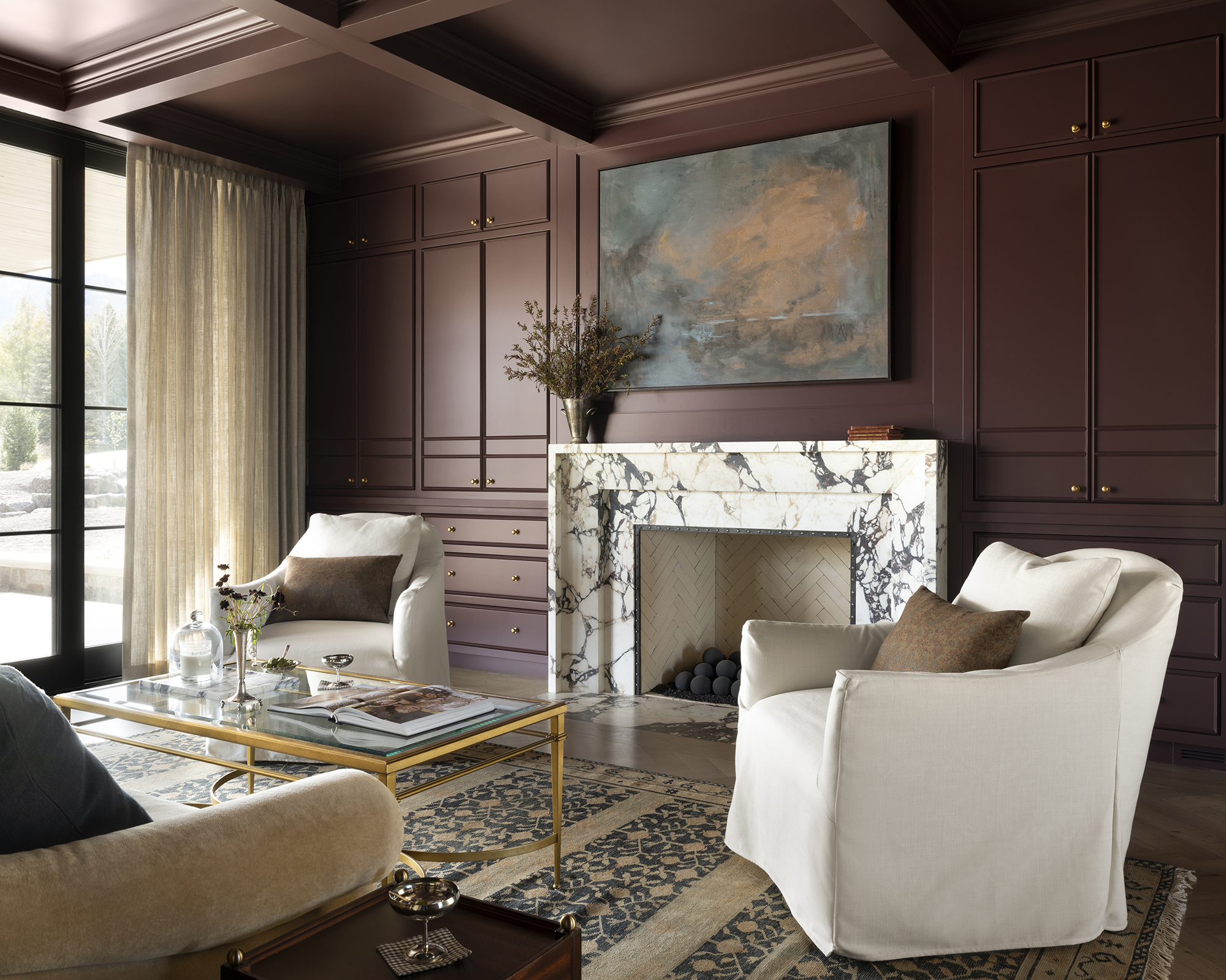 a large living room with brown walls and white furniture and marble fireplace