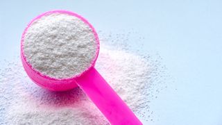 A pink scoop filled with powder laundry detergent