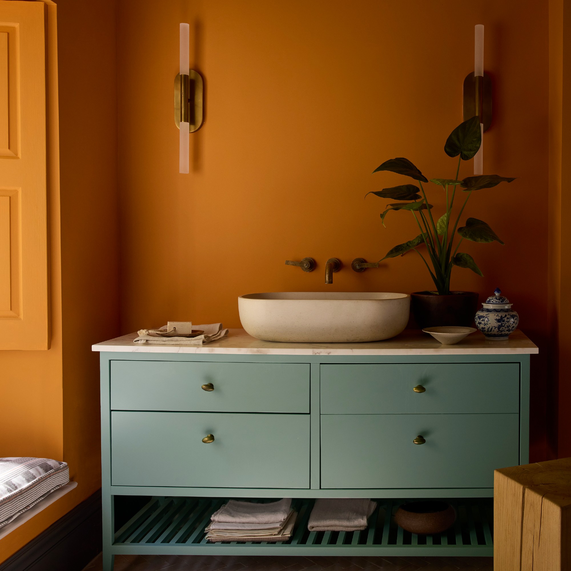 A bathroom painted in Little Greene's new Ashes of Marigold orange shade with Perpetual Blue on the under-sink cabinet