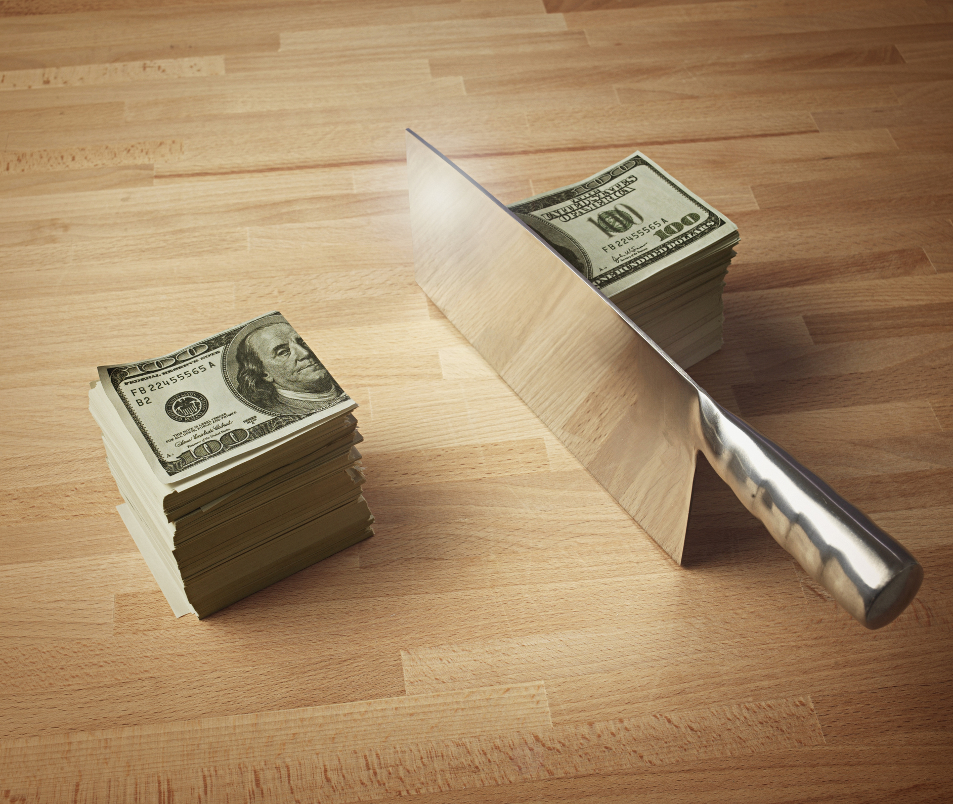 Meat Cleaver Cutting a Stack of Money in Half