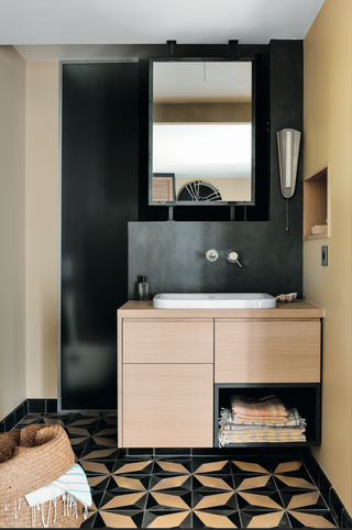 A bathroom with black walls, and wooden vanity