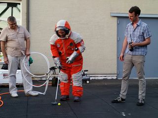 NASTAR space training center director Brienna Henwood puts a golf ball while wearing a Final Frontier Design spacesuit during the Brooklyn, New York-based company's Spacesuit Experience launch party atop a Brooklyn Navy Yards rooftop on Aug. 28, 2014.