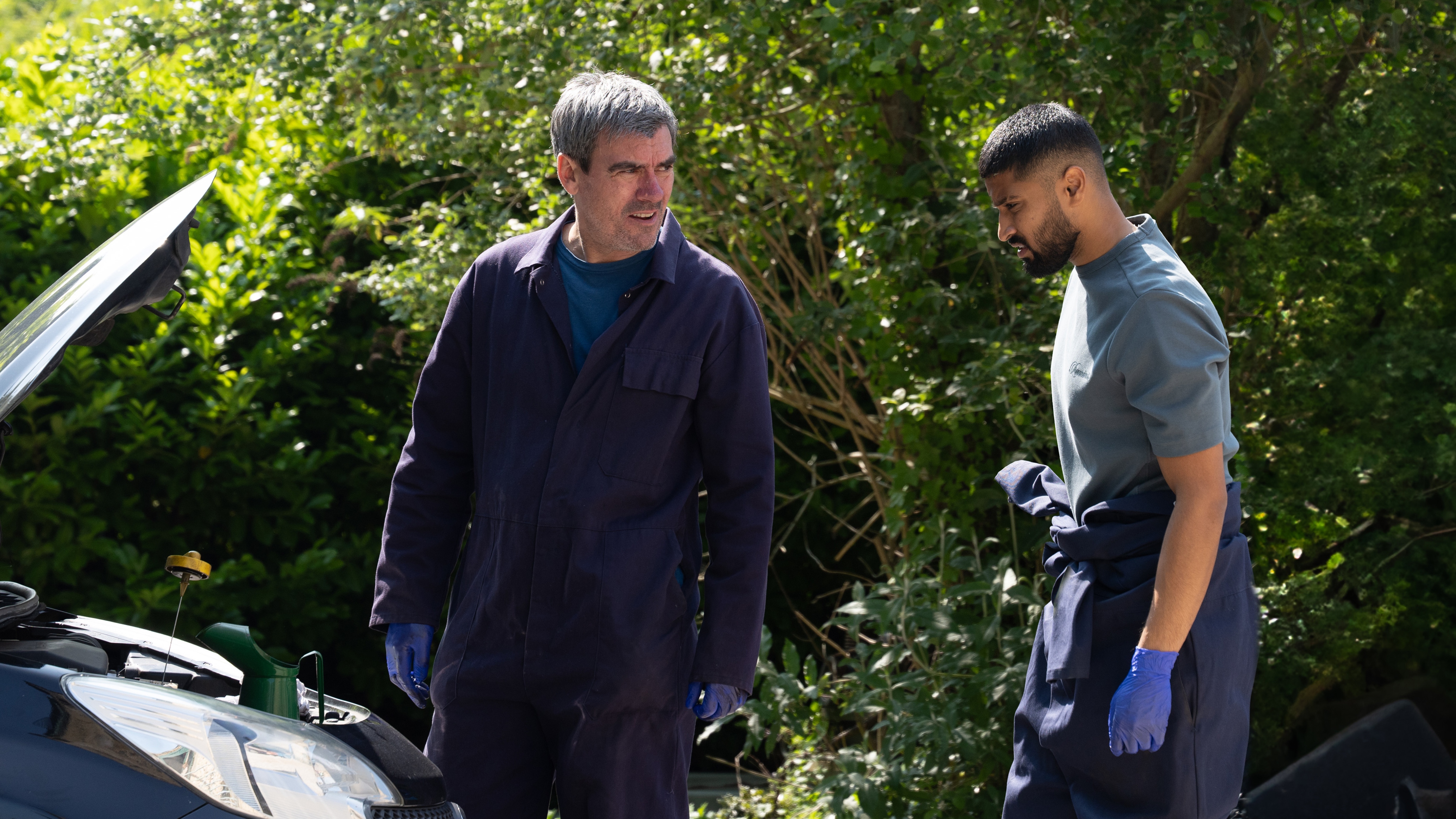 Cain and Kammy talking by an open car bonnet
