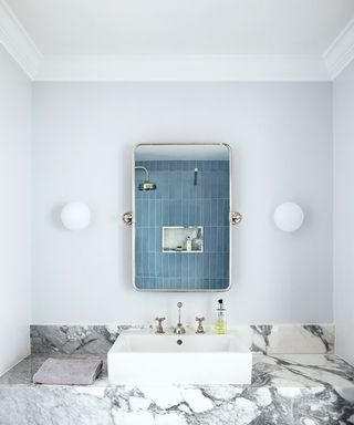 bathroom with marble surface, white sink and mirror