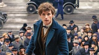 Next Scamander (Eddie Redmayne) climbs steps with a crowd of people behind him.