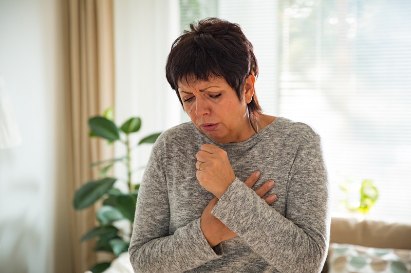 A stock photo of a woman coughing.