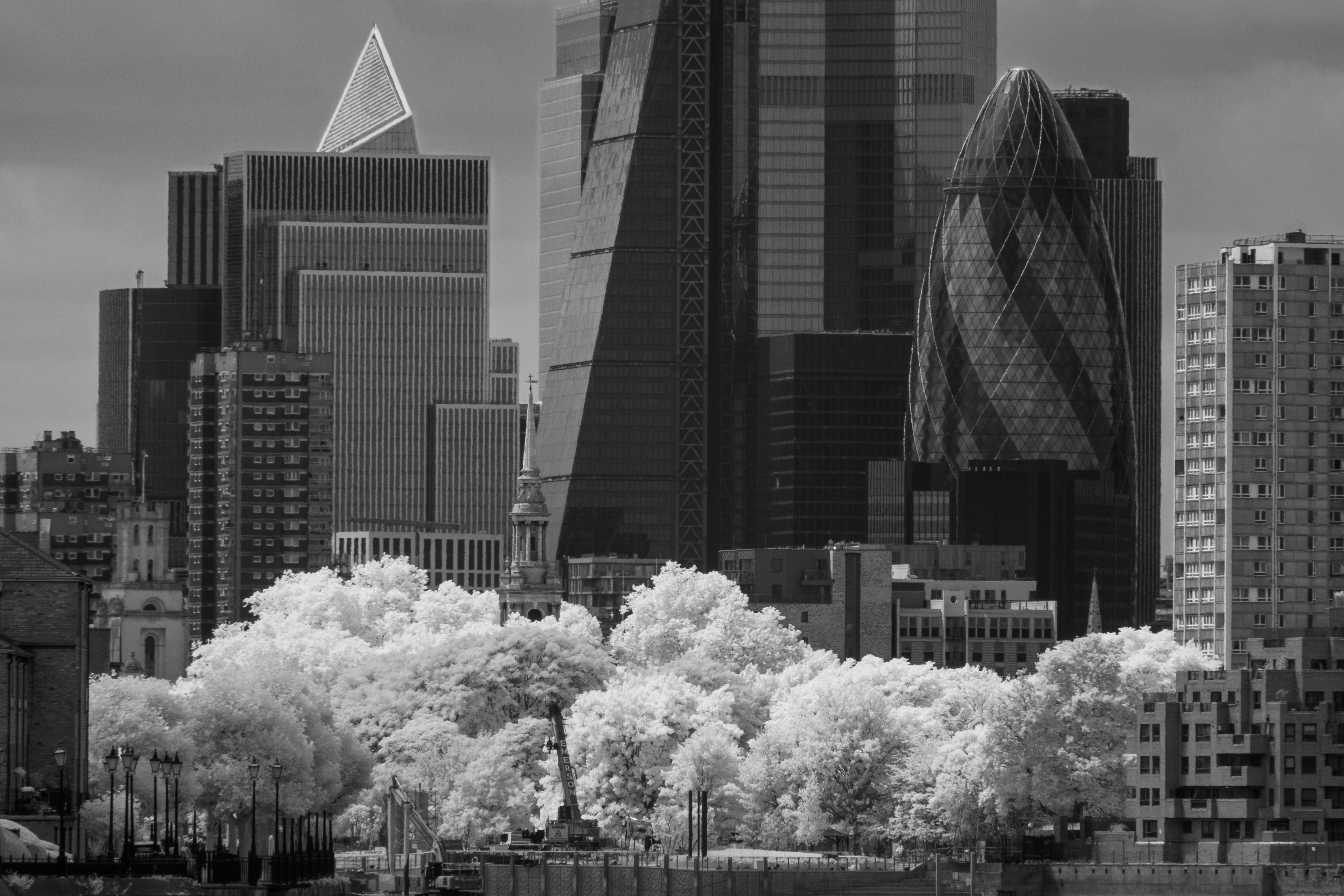 A church surrounded by trees and London skyscrapers
