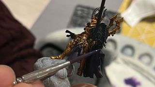 Someone holding a Warhammer model paints it with a brush