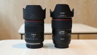 Canon RF 35mm f/1.4L VCM lens next to a Canon EF 35mm f/1.4L II USM lens on a wooden surface