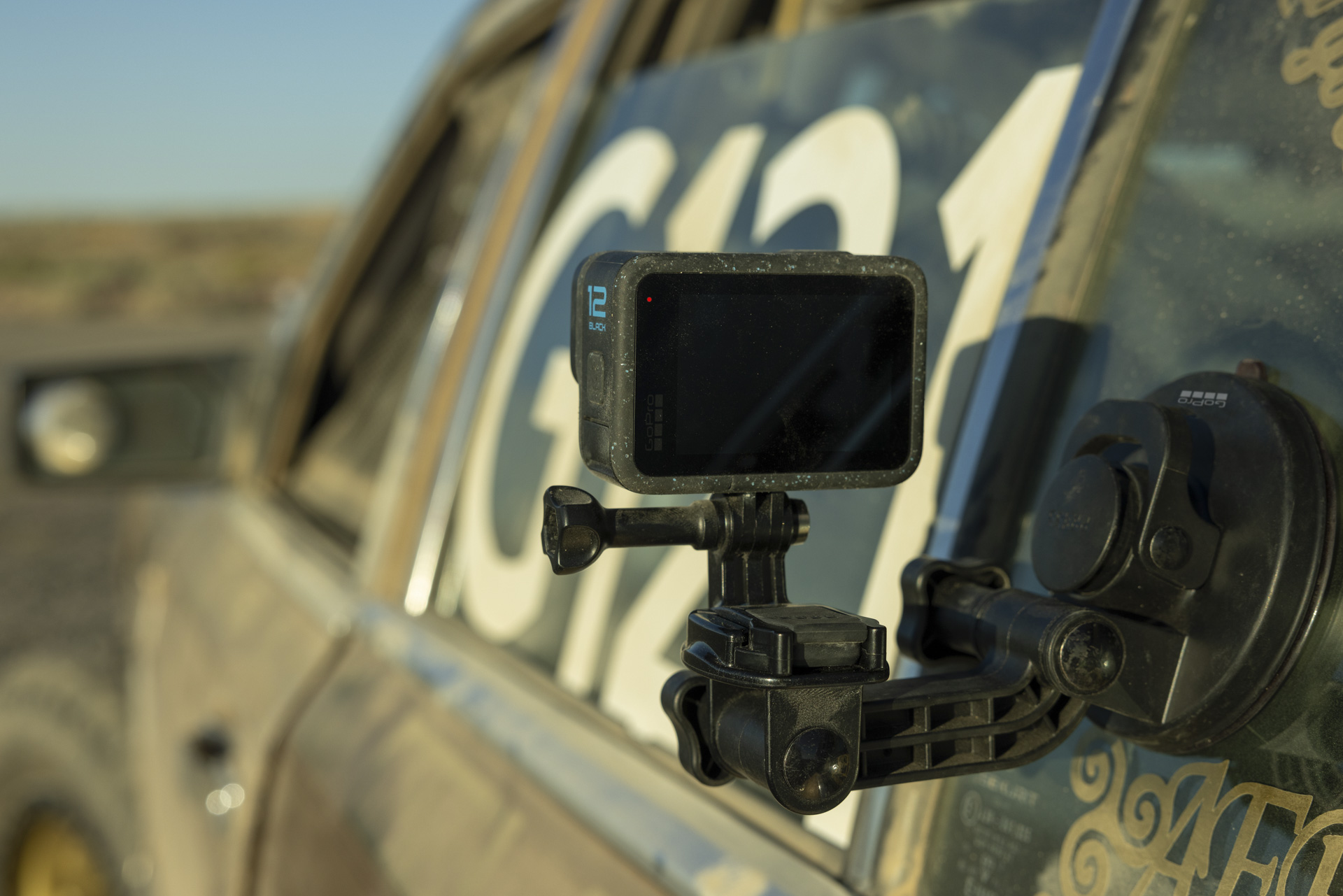 GoPro Hero 12 Black mounted to the outside of a rally car in a dusty terrain