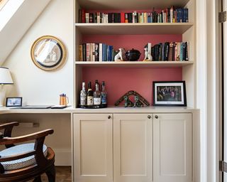 Home office with red walls, cream cabinets and shelving