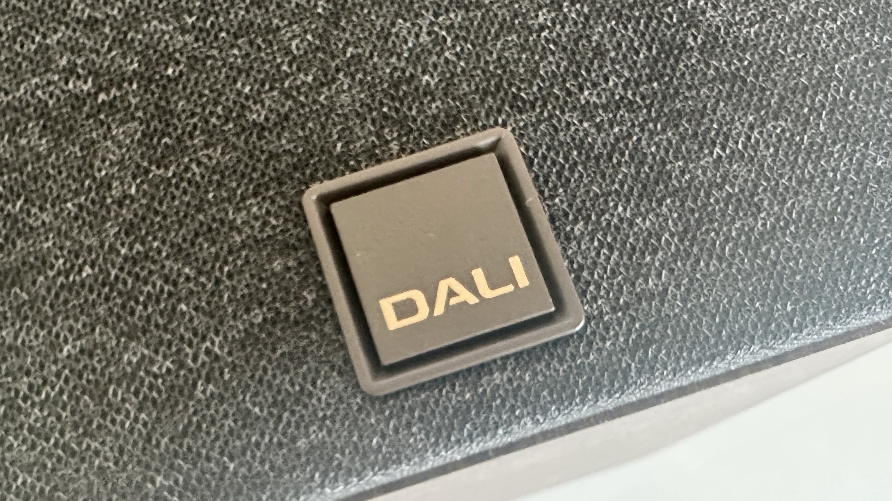 Closeup of the Dali logo on the magnetically attached grill of the Dali Kupid bookshelf speaker.