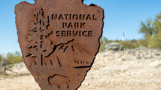 Metal National Park Sign on Gate at entrance to Saguaro wilderness